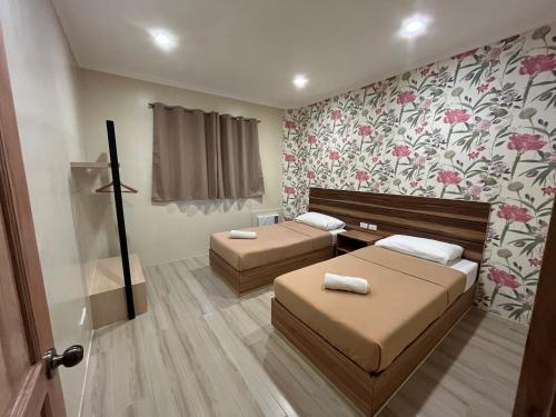 two beds in a room with floral wallpaper at Red Knight Gardens in Davao City