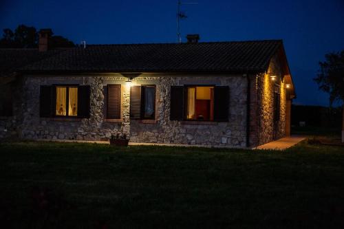 a stone house with lights on the windows at night at Agriturismo Le Chiocciolaie Appartamento 1 - Appartamento 3 in Podere Cernaia