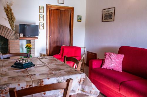 a living room with a table and red chairs at Agriturismo Le Chiocciolaie Appartamento 1 - Appartamento 3 in Podere Cernaia