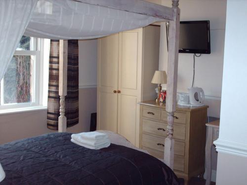a bedroom with a canopy bed and a dresser at The Camberley in Harrogate