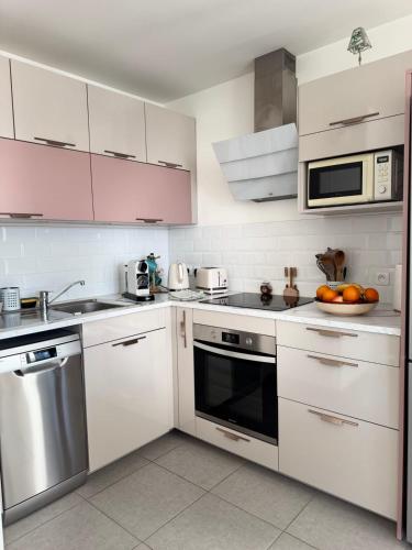 - une cuisine avec des armoires blanches et un bol d'oranges sur le comptoir dans l'établissement Le Secret des Collines - South facing balcony, à Aix-les-Bains