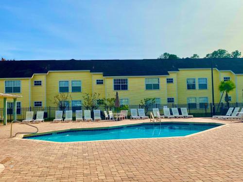 una piscina con sillas y un edificio amarillo en Grand Laguna 3BR Penthouse Near Disney Parks, en Kissimmee