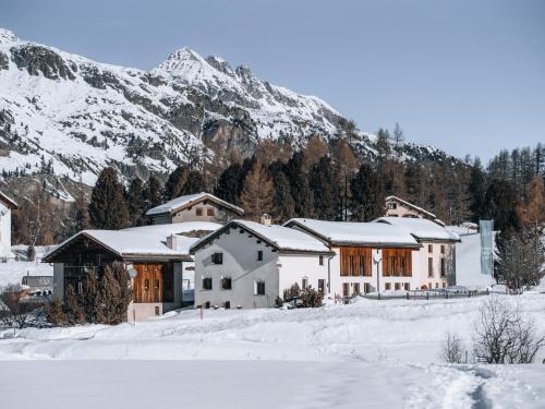 a house in the snow with a mountain in the background at Hotel Chesa Pool in Sils Maria