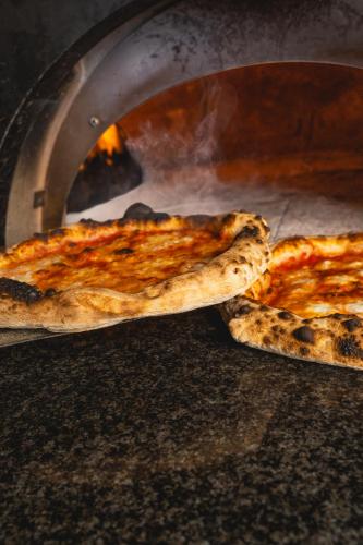 two pizzas are being cooked in an oven at Sant'Angelo, Matera - Small Luxury Hotels in Matera