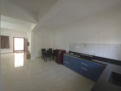 a large kitchen with blue cabinets and black chairs at Blossom Service Apartment in Mysore