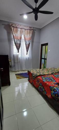 a bedroom with a bed and a ceiling fan at d'esaku homestay in Penaga