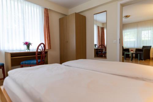 a hotel room with a large white bed and a desk at Easy Stay by Hotel La Perla in Ascona