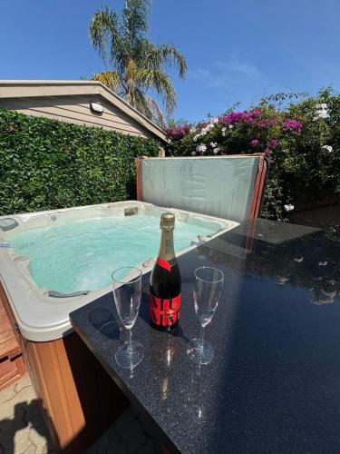 a bottle of wine and glasses on a table next to a hot tub at Spa Retreat Glenelg East in Glenelg