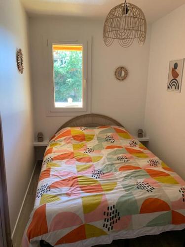 - un lit avec une couette colorée dans une chambre dans l'établissement Charmant T2 rénové proche plage et commerces, à Bormes-les-Mimosas