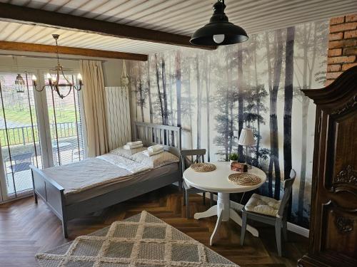 a bedroom with a bed and a table and a window at Apartament Leśny in Zamość