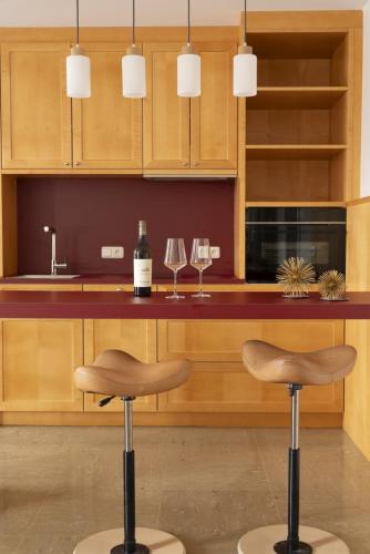 a kitchen with two bar stools and wine glasses at Landhaus zum Caphenstain in Gutendorf