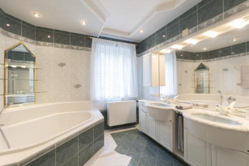 a large bathroom with two sinks and a tub and a tubermott at Landhaus zum Caphenstain in Gutendorf