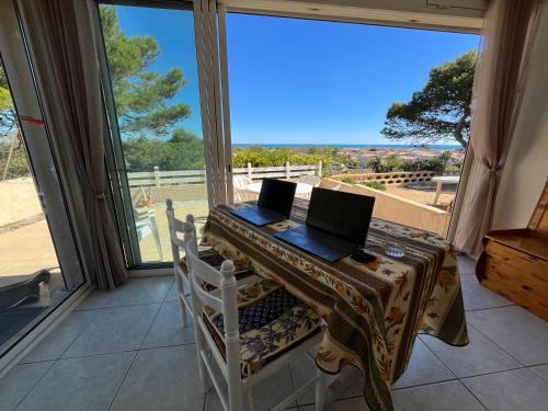 a laptop computer sitting on a table in front of a window at Panorama Mer in Saint Pierre La Mer