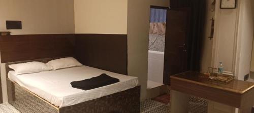 a small bedroom with a bed and a table at Blooming Rooms in Guwahati