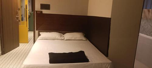 a bedroom with a bed with a black pillow on it at Blooming Rooms in Guwahati