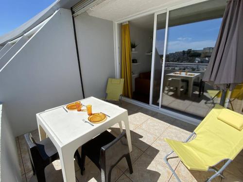 Cette chambre dispose d'un balcon avec une table et des chaises blanches. dans l'établissement Appartement 4 couchages CAP D'AGDE NATURISME CN030-309, au Cap d'Agde