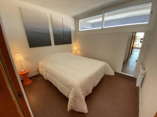 une chambre avec un lit blanc et une fenêtre dans l'établissement Appartement 4 couchages CAP D'AGDE NATURISME CN030-309, au Cap d'Agde