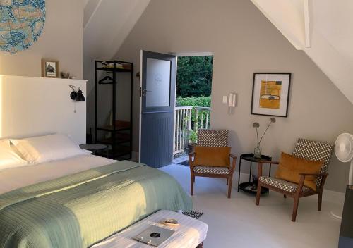 una camera da letto con letto, sedie e balcone di The Studio in Knysna a Knysna