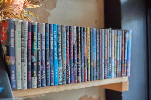 a row of books sitting on a book shelf at KARASUYA GuestHouse in Takasaki