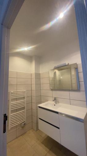 une salle de bain blanche avec un lavabo et un miroir dans l'établissement Le Petit paradis, à Aregno