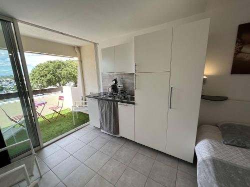 Il comprend une cuisine avec des placards blancs et offre une vue sur une terrasse. dans l'établissement Studio 2 couchage Cap d'Agde Naturisme CN040-633, au Cap d'Agde