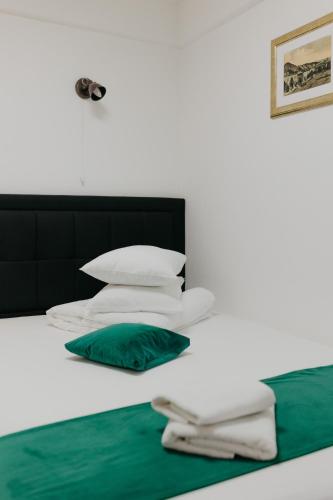 a bed with white pillows and a green pillow at Pensiunea Pictorilor in Baia Mare