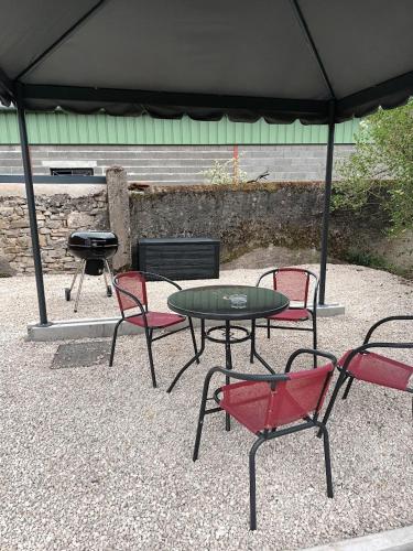 a patio with a table and chairs and a grill at La Petite Lorraine in Socourt