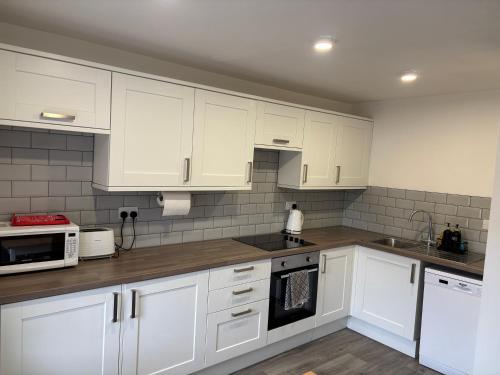 a kitchen with white cabinets and white appliances at 16 Macgregor court, Oban in Oban