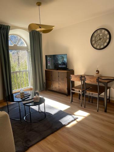 - un salon avec une table et une horloge murale dans l'établissement Coquet appartement, à Ussat