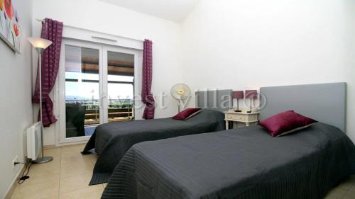 une chambre d'hôtel avec deux lits et une fenêtre dans l'établissement 3 bedroom penthouse apartment near cannes, à Mandelieu-la-Napoule