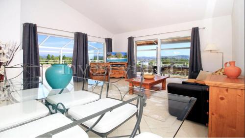 un salon avec une table, des chaises et des fenêtres dans l'établissement 3 bedroom penthouse apartment near cannes, à Mandelieu-la-Napoule
