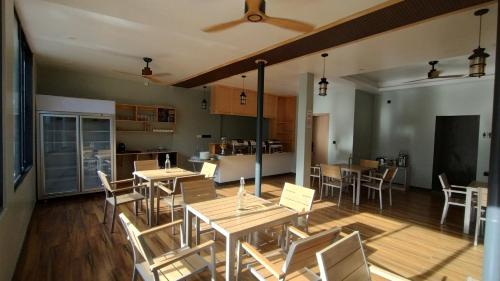 a dining room with tables and chairs and a kitchen at Madi Grand Maldives in Fulidhoo