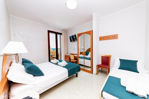 a hotel room with two beds and a chair at Hotel Alba in Torre Lapillo