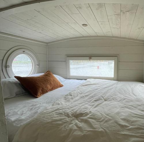 un grand lit blanc dans une chambre avec une fenêtre dans l'établissement Bateau traditionnel de Loire face au château d'Angers, à Angers