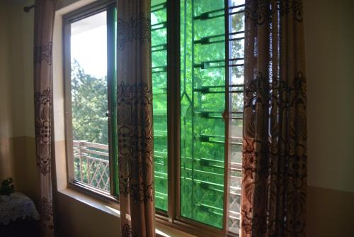 a window with a view of a green yard at Riasat Home Stay - Nathia Gali Road in Bāzār