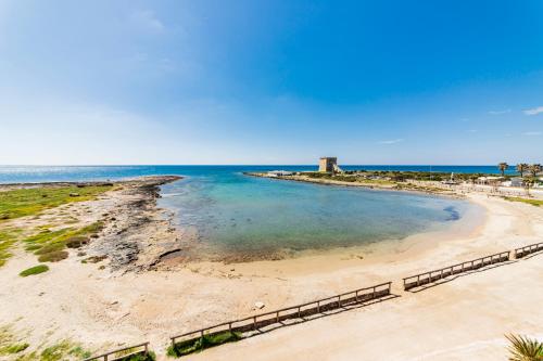 a view of a beach with a lighthouse in the distance at Hotel Alba in Torre Lapillo
