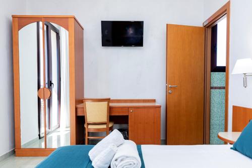 a bedroom with a bed and a desk with a television at Hotel Alba in Torre Lapillo