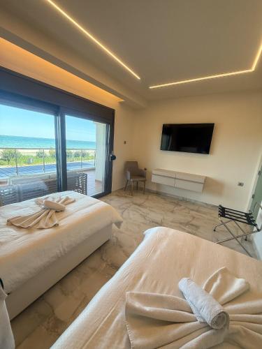 a bedroom with two beds and a large window at Aqua Mare Luxury Apartments in Paralia Katerinis