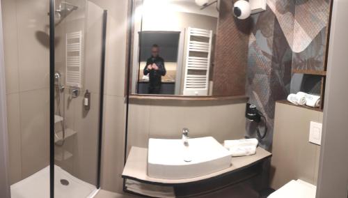 a man taking a picture of a bathroom with a sink at Apartament e310 - Bel Mare Międzyzdroje in Międzyzdroje