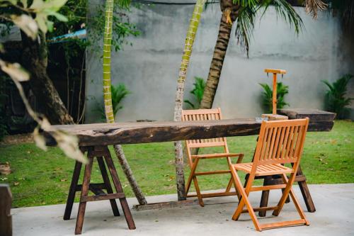 a wooden table with two chairs and palm trees at River Nest Hostel in Kampot