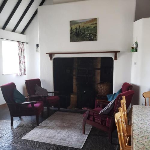 a living room with chairs and a fireplace at Bluebell Cottage 3 bedroom in Louisburgh