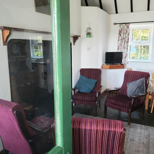 a living room with three chairs and a television at Bluebell Cottage 3 bedroom in Louisburgh