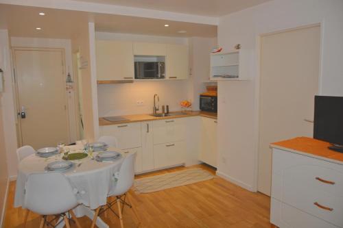 a white kitchen with a table and chairs and a television at Elégant T2 près de la plage et en hyper centre in Arcachon