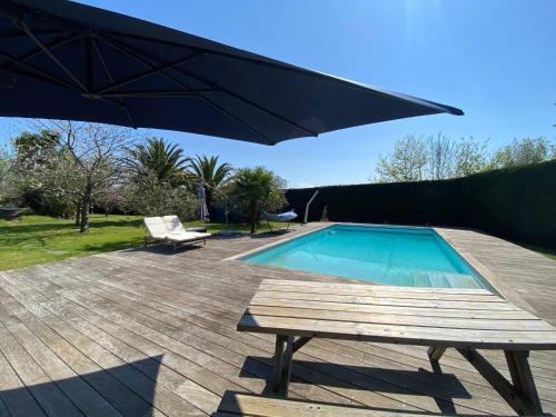 - une piscine avec une table de pique-nique et un parasol dans l'établissement Villa Coco - Prestations haut de gamme, à Arcangues