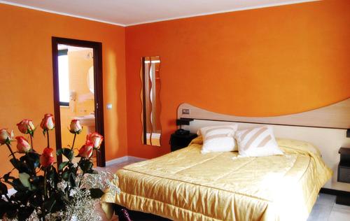 um quarto com uma parede laranja com uma cama e flores em Hotel Del Sole em Pastorano