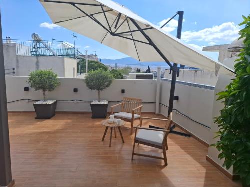 a patio with a white umbrella on a roof at Luxury transformable loft in Athens
