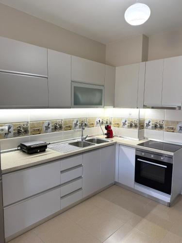 a kitchen with white cabinets and a sink at Velipoja Apartment in Velipojë