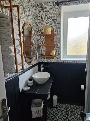 une salle de bain avec un lavabo et un miroir dans l'établissement Gîte les 13 lavoirs d'antan, à Saint-Pierre-Église