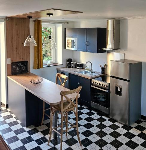 une cuisine avec des placards bleus, une table et un comptoir dans l'établissement Gîte les 13 lavoirs d'antan, à Saint-Pierre-Église