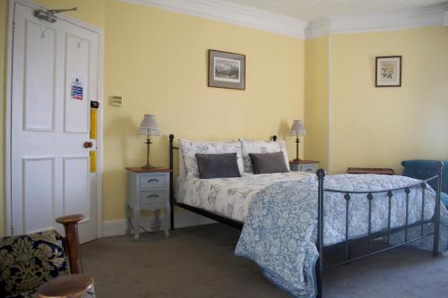 1 dormitorio con 1 cama, 2 mesas y puerta en Woodlands, Teignmouth, en Teignmouth